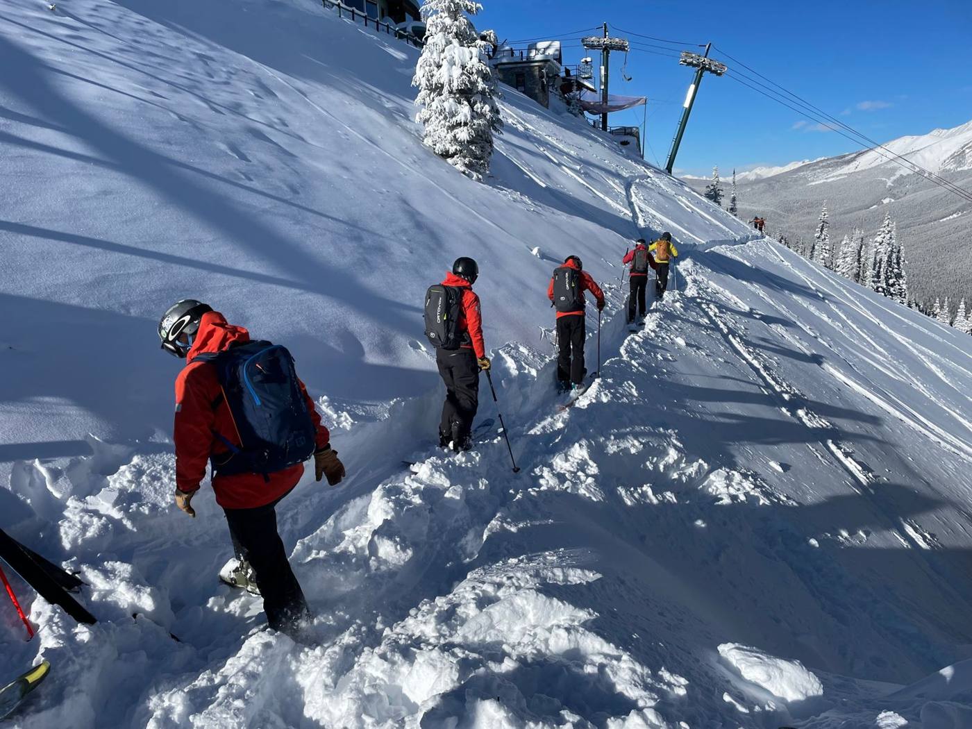Skiers climbing a snowy slope beside a chairlift