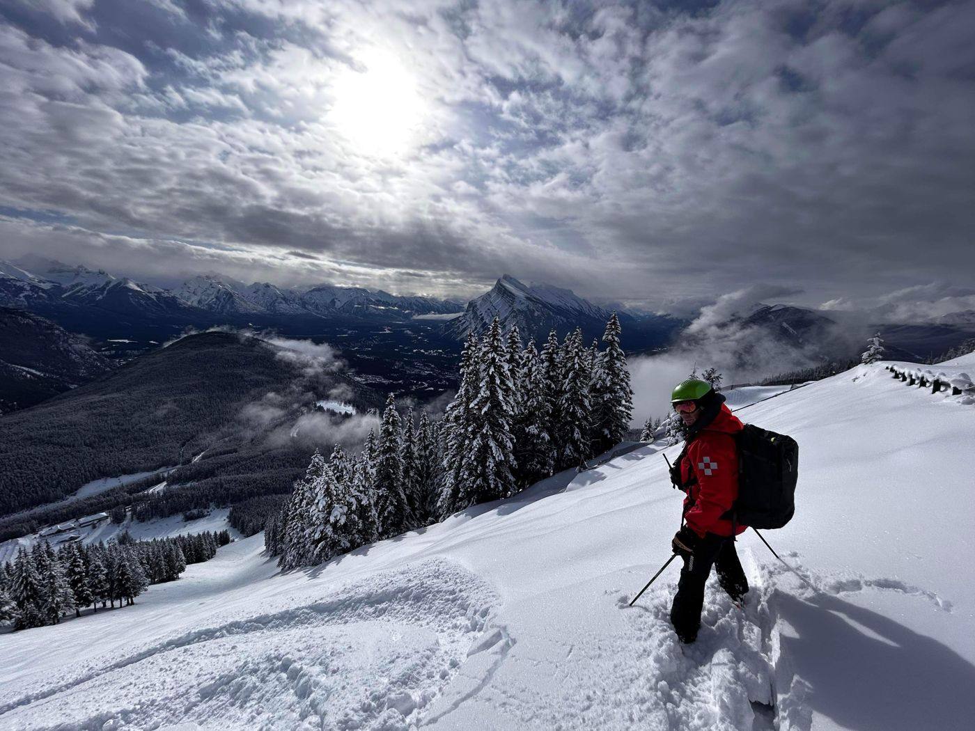 Joe McKay in a red ski patrol jacket on a snowy ridge above the Bow Valley